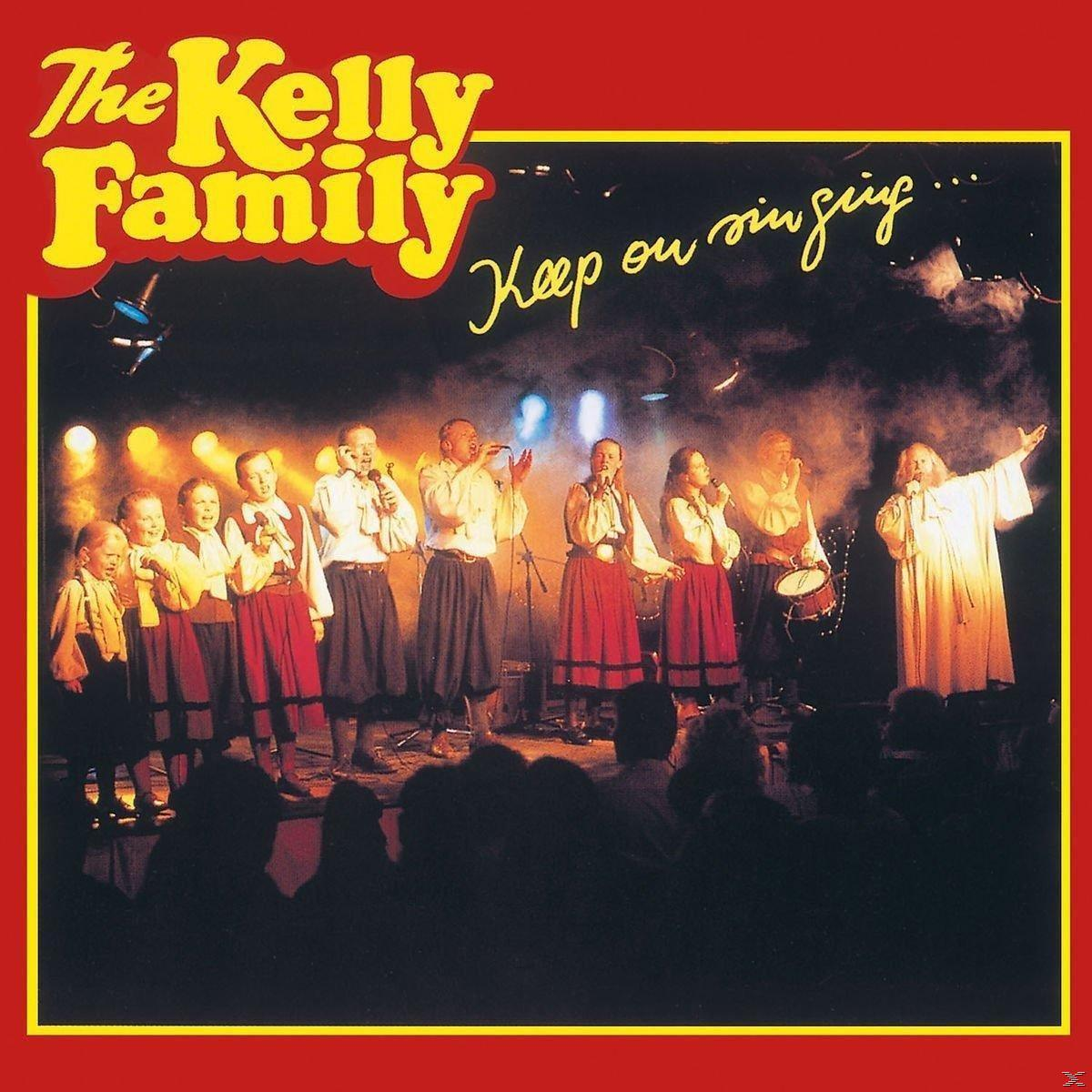 Albumcover: The Kelly Family tritt auf einer Bühne mit einer Band auf.