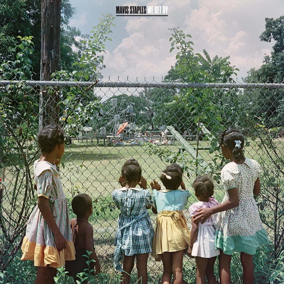 Albumcover: Kinder schauen durch einen Zaun auf einen Spielplatz. Text: Mavis Staples, We Get By. Grüne Bäume und Himmel.