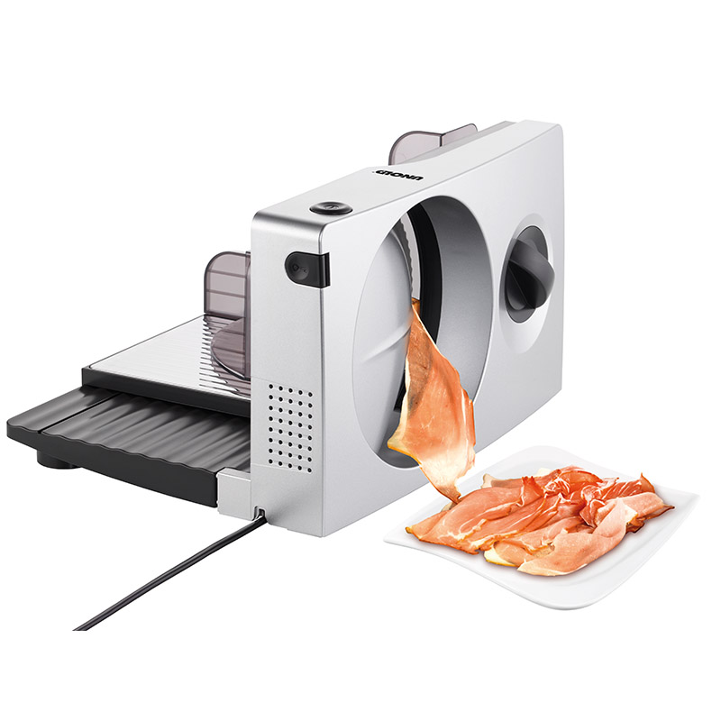 Silberner Fleischschneider, eine Scheibe Fleisch wird auf einen weißen Teller geschnitten.