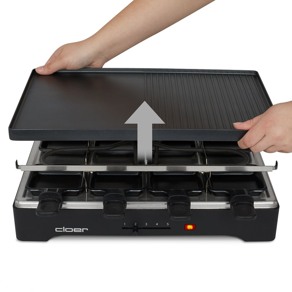 Hände heben eine schwarze Grillplatte von einem Raclette-Gerät. Das Gerät hat acht kleine Pfannen und ein Bedienfeld mit rotem Licht.