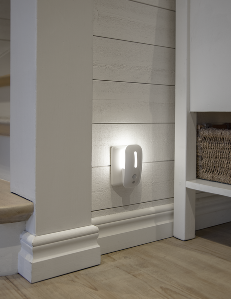 Luce notturna bianca su muro bianco, con pavimento in legno e modanature.