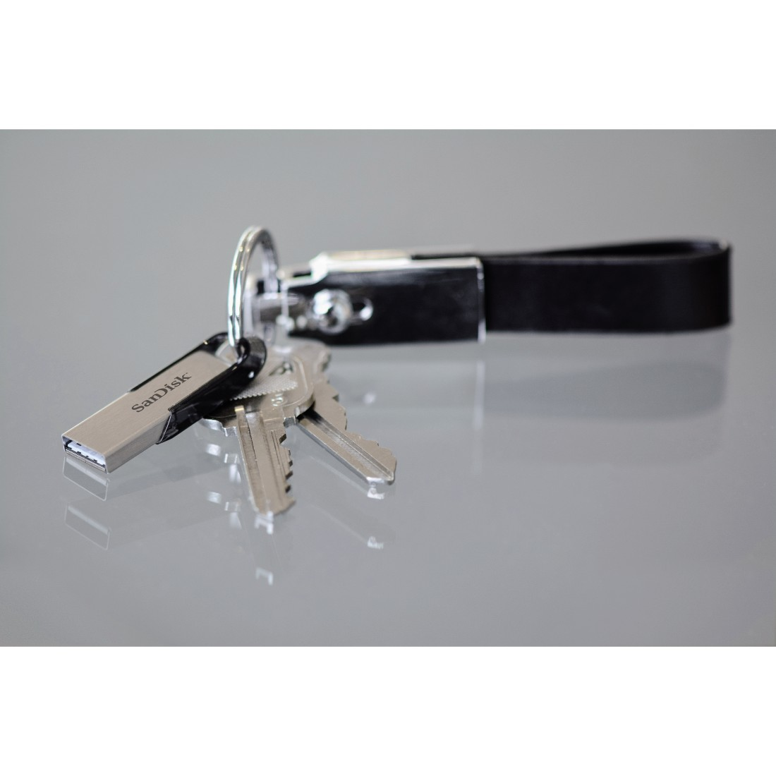 A keychain with keys and a silver SanDisk USB flash drive.