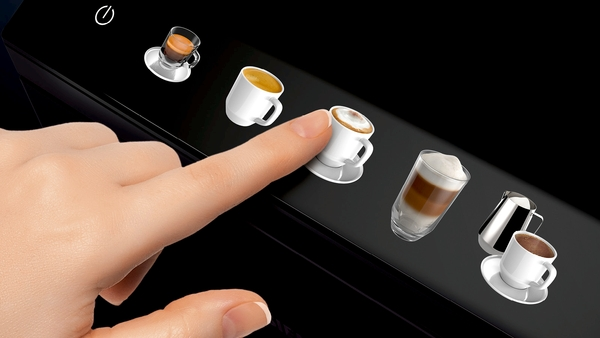 Eine Hand drückt einen Knopf mit einem Kaffeetassen-Symbol auf einer schwarzen Touchscreen-Oberfläche.