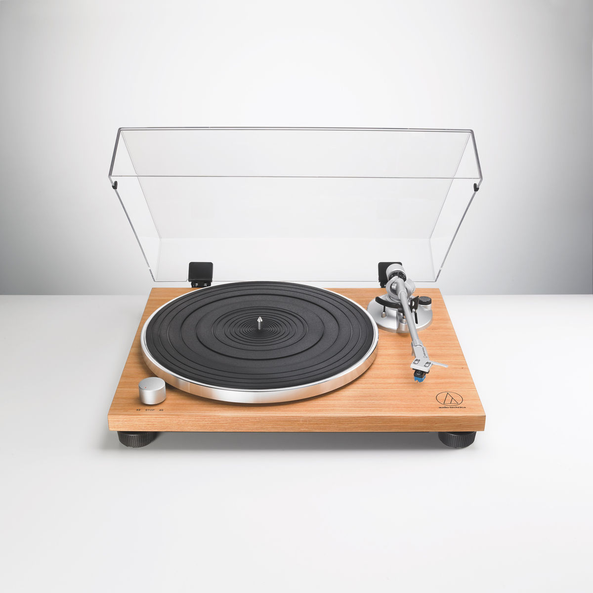 Platenspeler met een houten basis, zwarte schotel, zilveren arm en een doorzichtige kap.