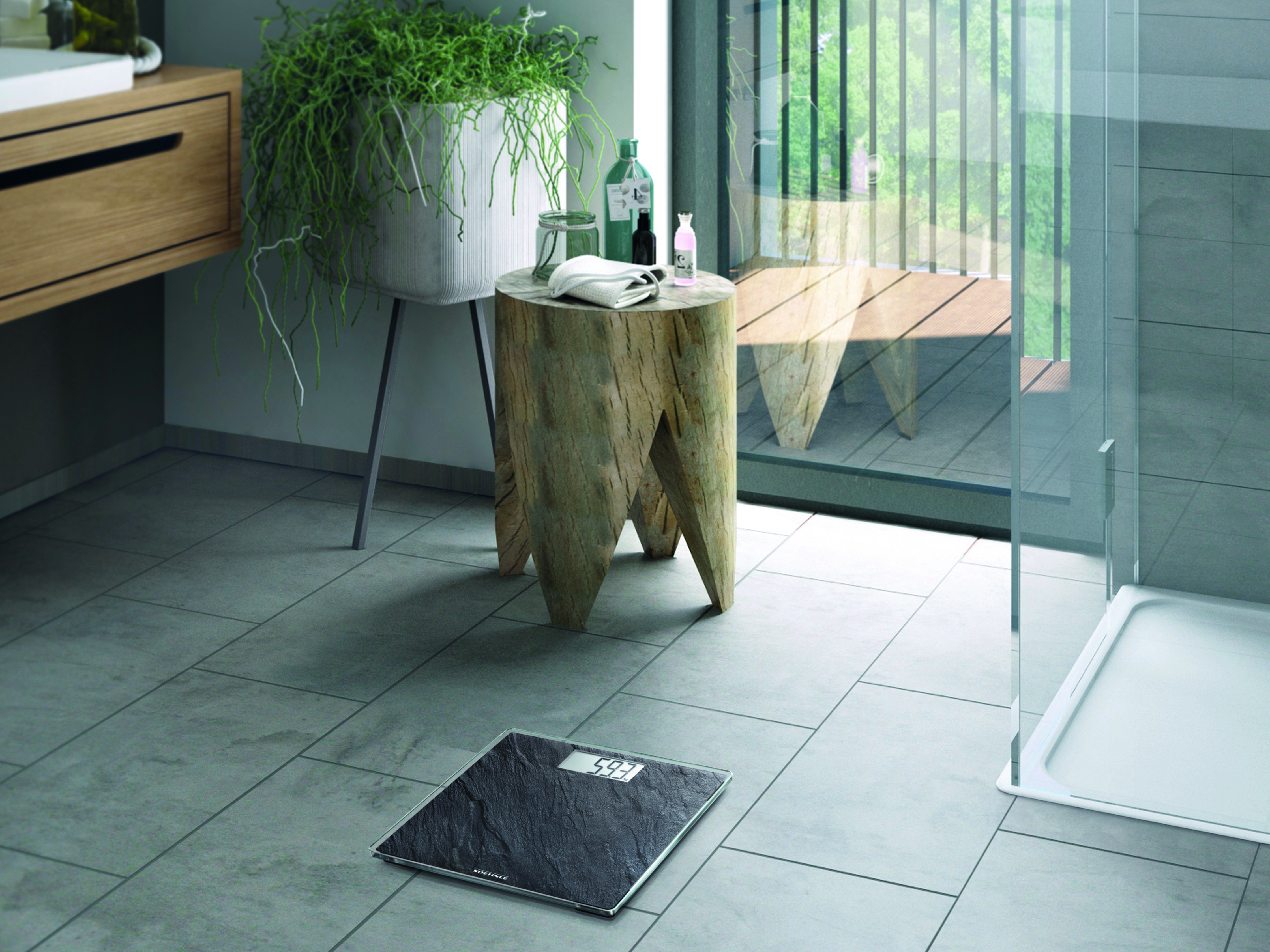 Badezimmer. Eine Waage steht auf dem Fliesenboden. Ein Baumstumpf-Tisch mit Toilettenartikeln, Balkon im Blick.