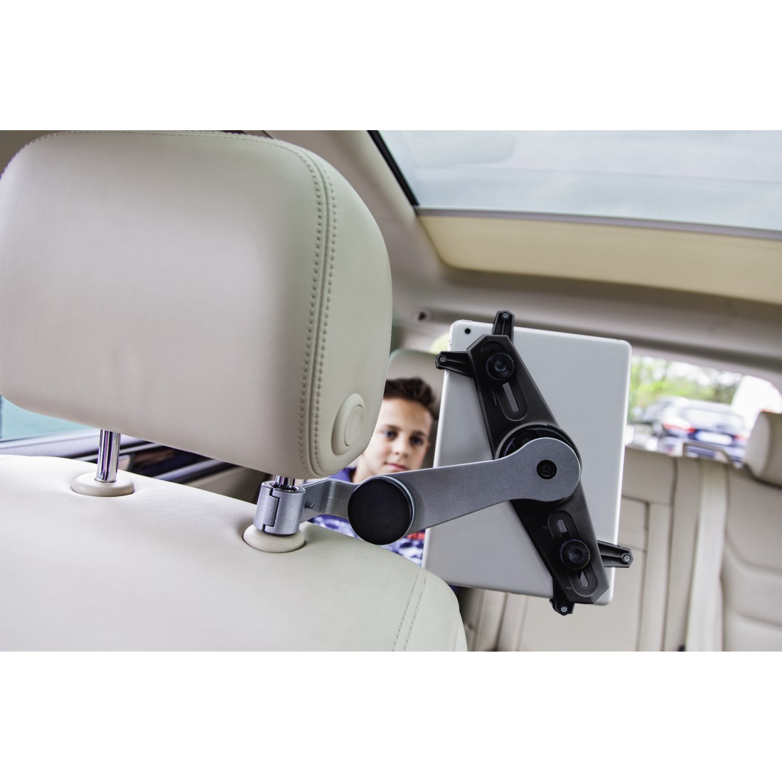Tablet holder mounted on a car headrest. A child is visible in the rearview mirror.