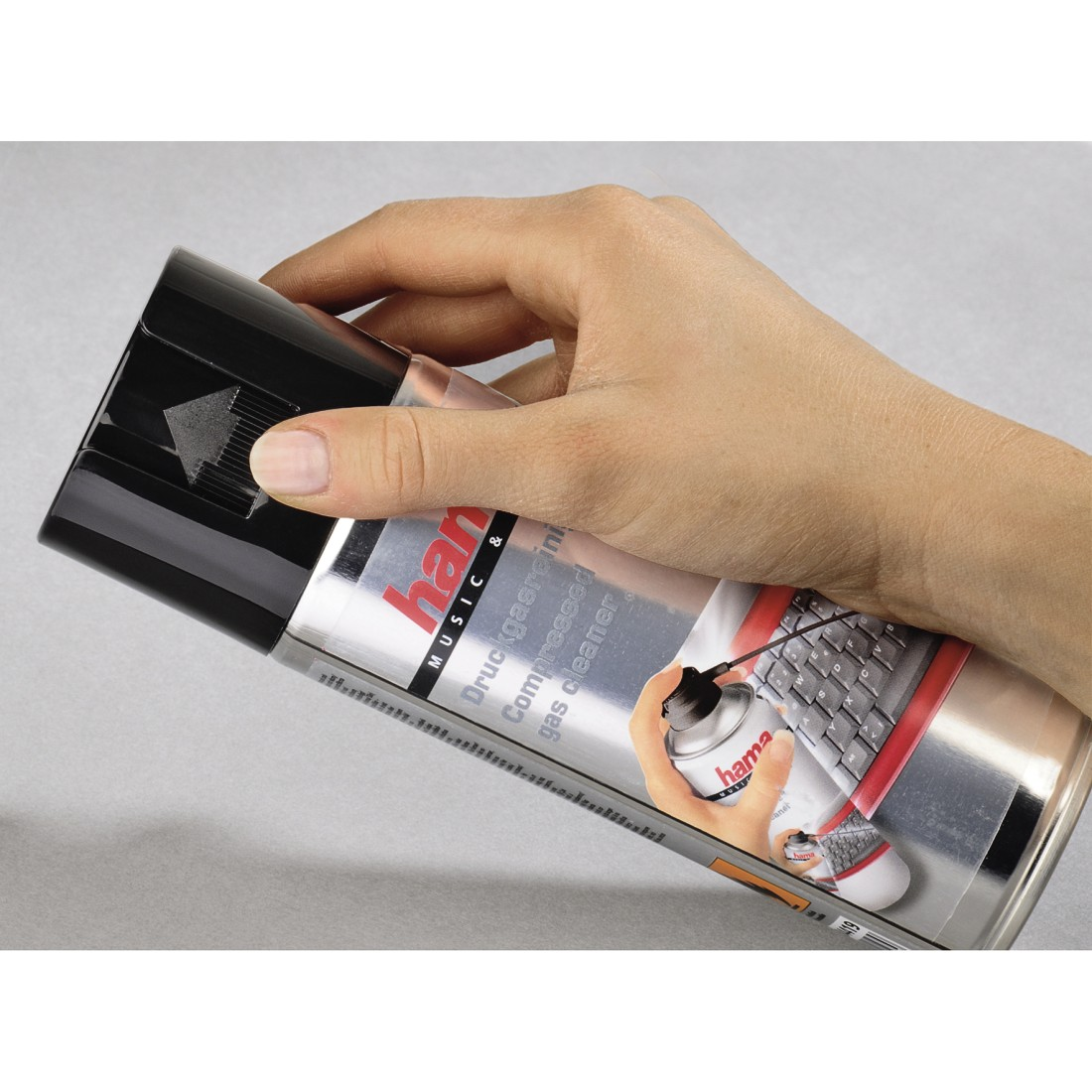 A hand holds a can of compressed gas cleaner. A picture of a keyboard is on the can.