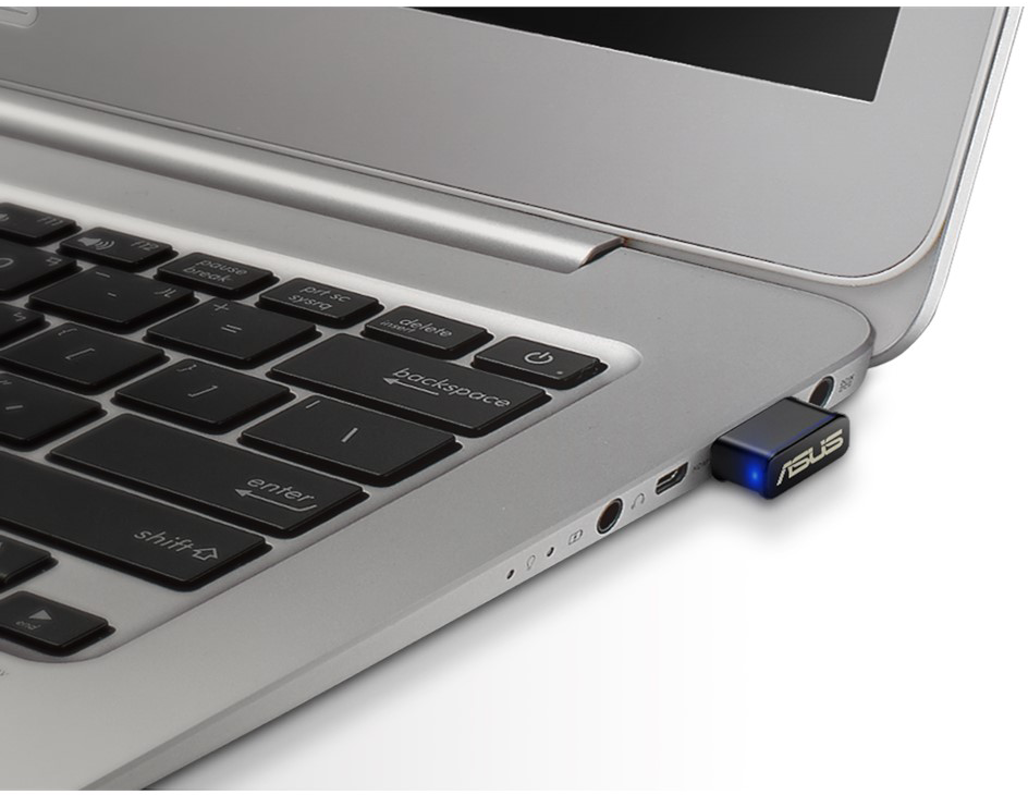 Ezüst laptop fekete billentyűzettel. Egy USB-s kulcs van csatlakoztatva.