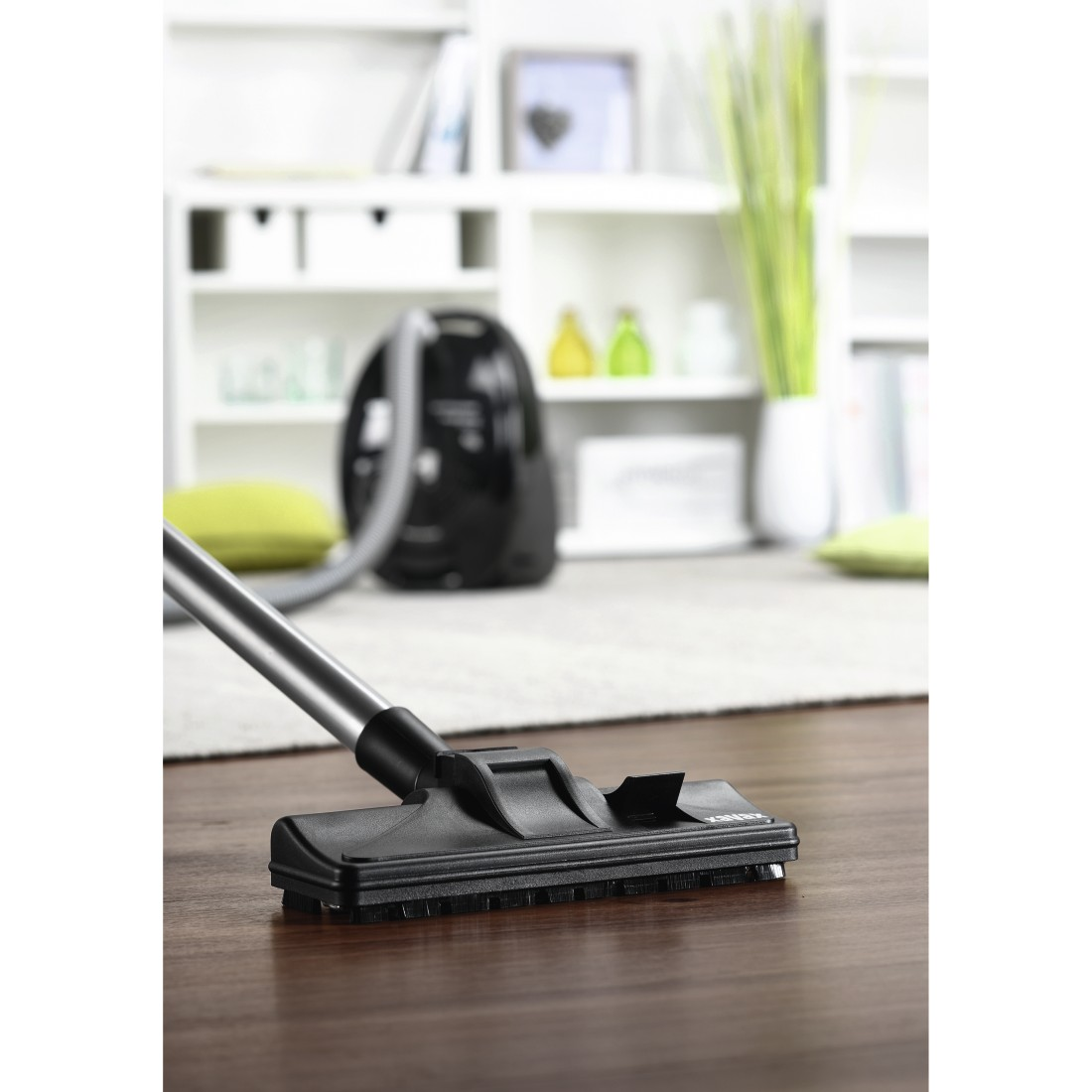 Vacuum cleaner head on a wooden floor. Black vacuum head, dark brown floor.