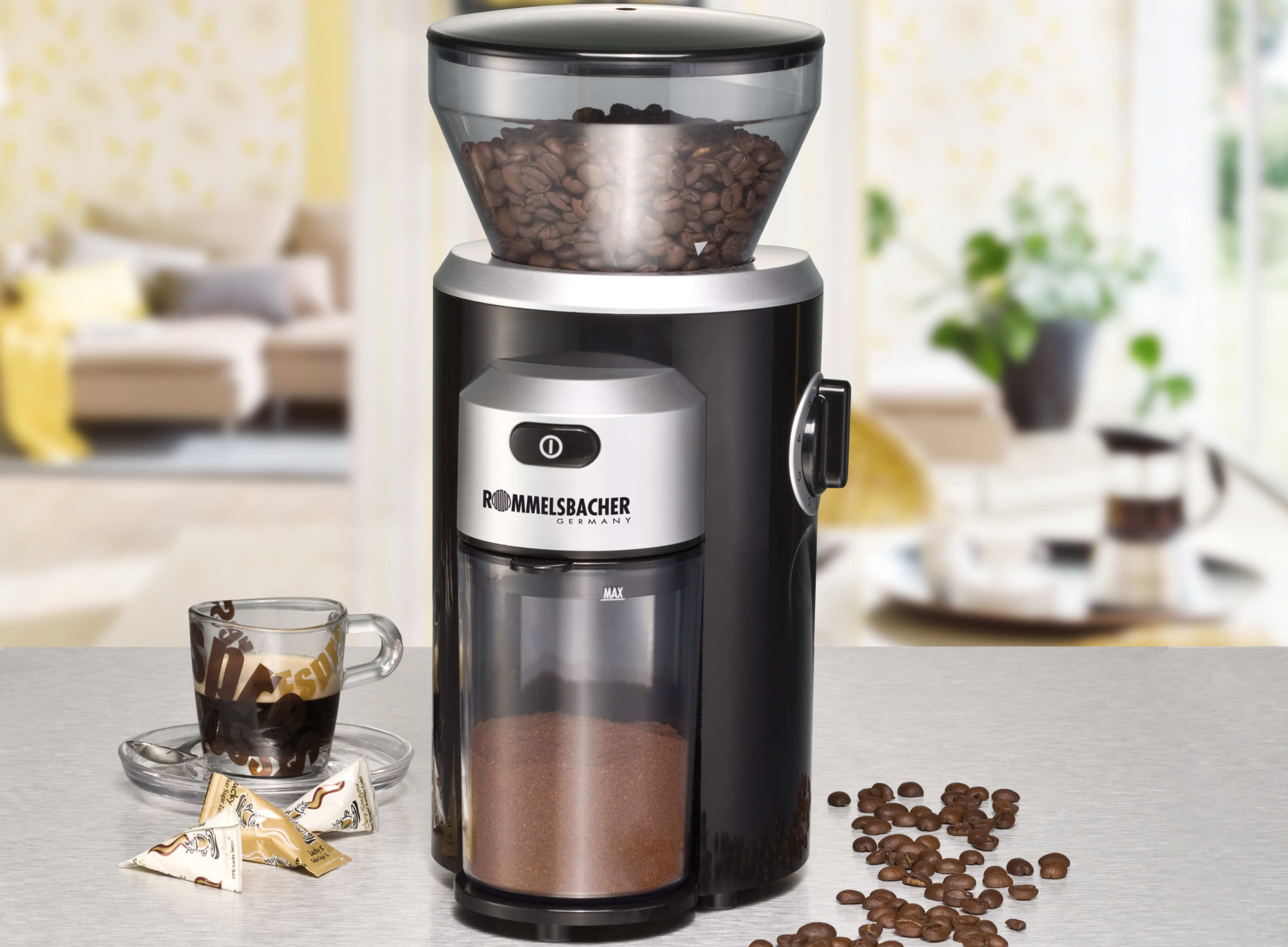 Kaffeemühle mit Bohnen. Hat einen transparenten Deckel, einen schwarzen Körper und einen Behälter für Kaffeepulver.