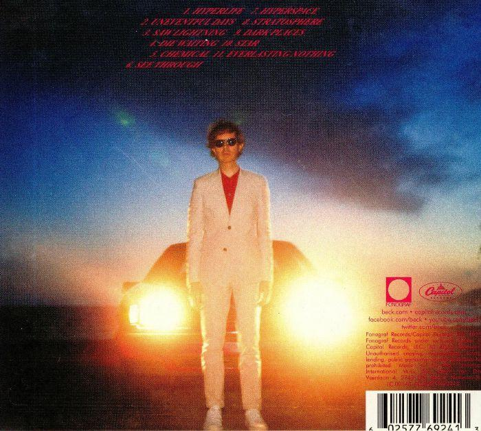 Albumcover von Beck, mit einem Mann in Weiß vor den Scheinwerfern eines Autos. Enthält Text und Logos.