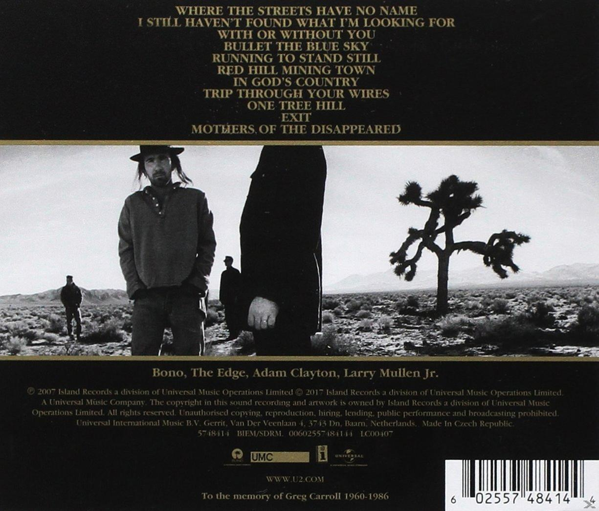 Albumcover mit einer Gruppe von Männern in einer Wüstenlandschaft, mit einem Baum und Text.