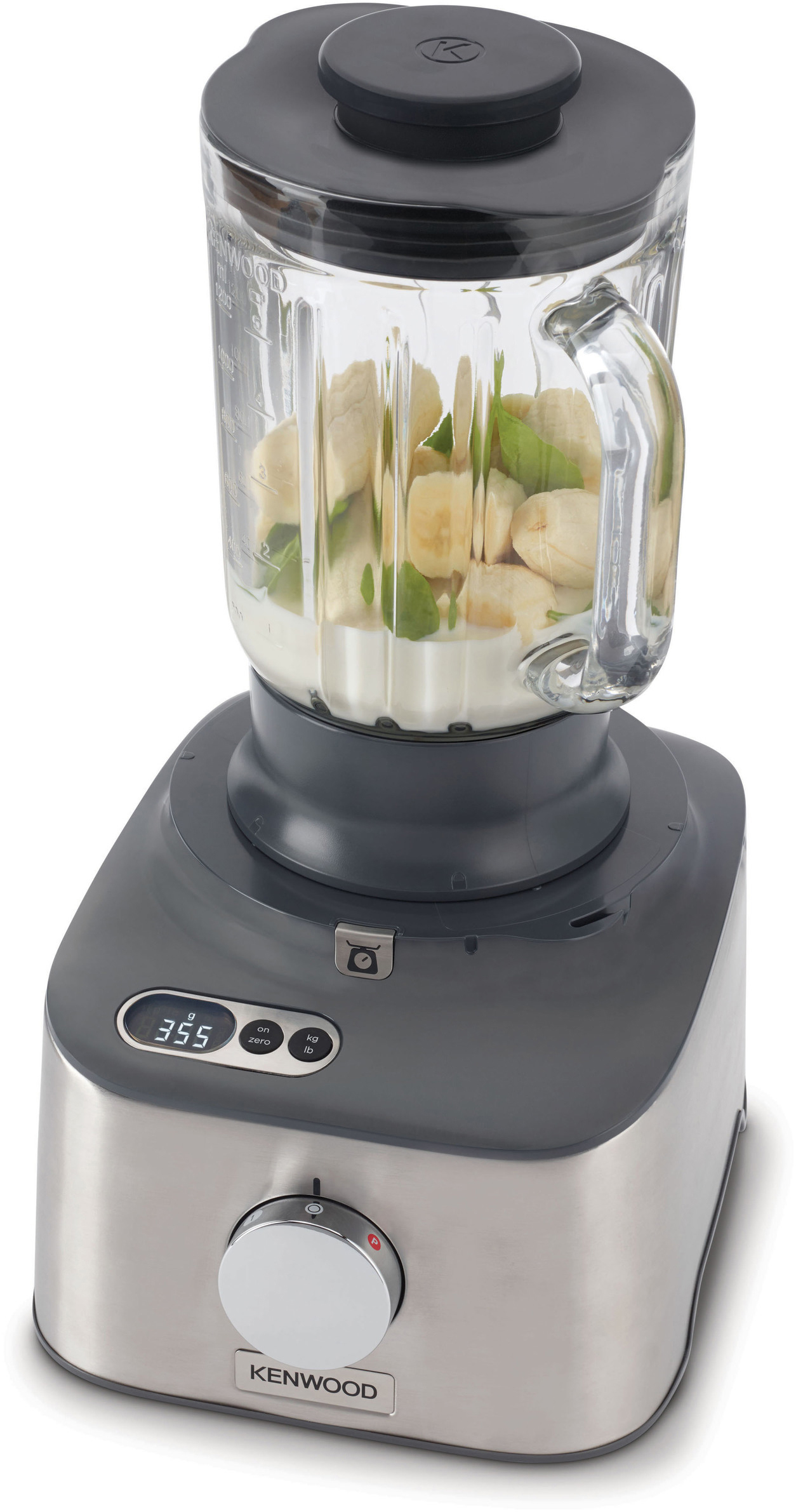 Mixer mit geschnittenen Bananen und grünen Blättern im Glaskrug.