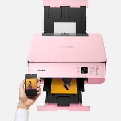 Impresora Canon Pixma rosa. Un teléfono muestra una imagen impresa. El papel está saliendo.