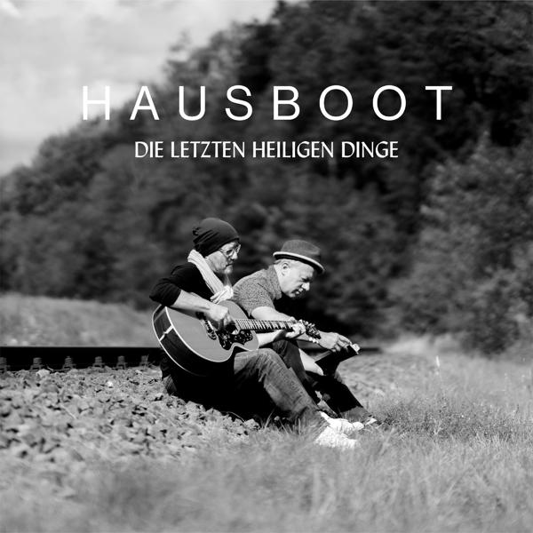 Schwarz-weiß Albumcover. Zwei Männer sitzen auf Bahngleisen, einer spielt Gitarre.