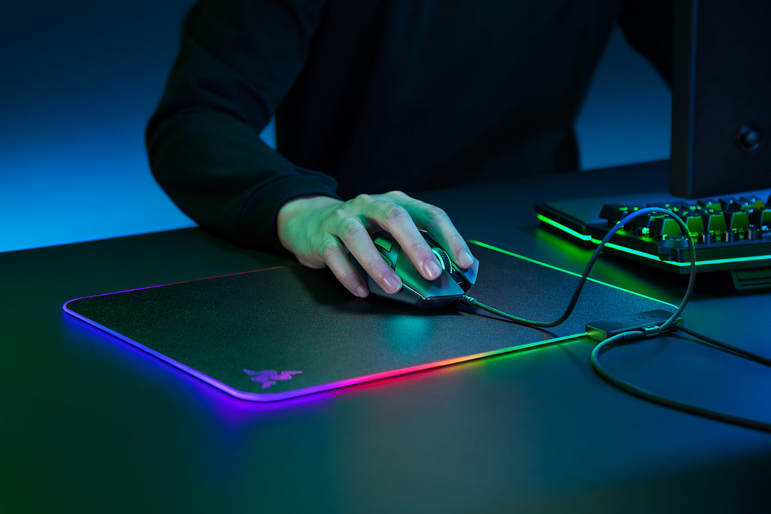 Main d'une personne utilisant une souris de jeu sur un tapis de souris avec éclairage coloré.