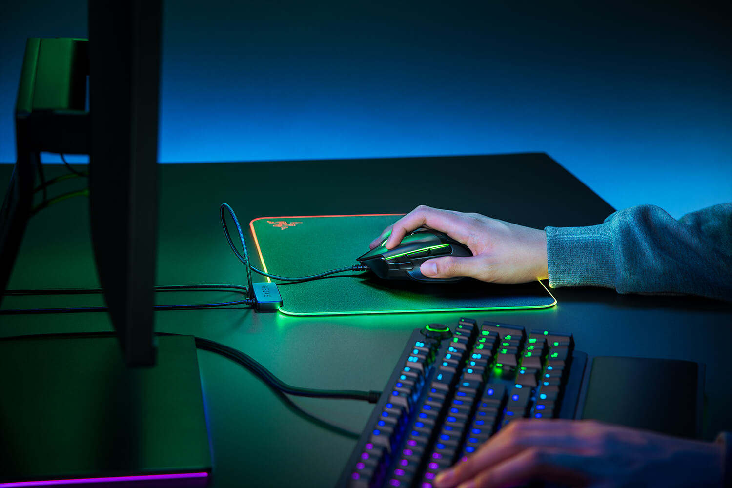 Une personne utilisant une souris et un clavier de jeu sur un bureau avec des lumières LED colorées.