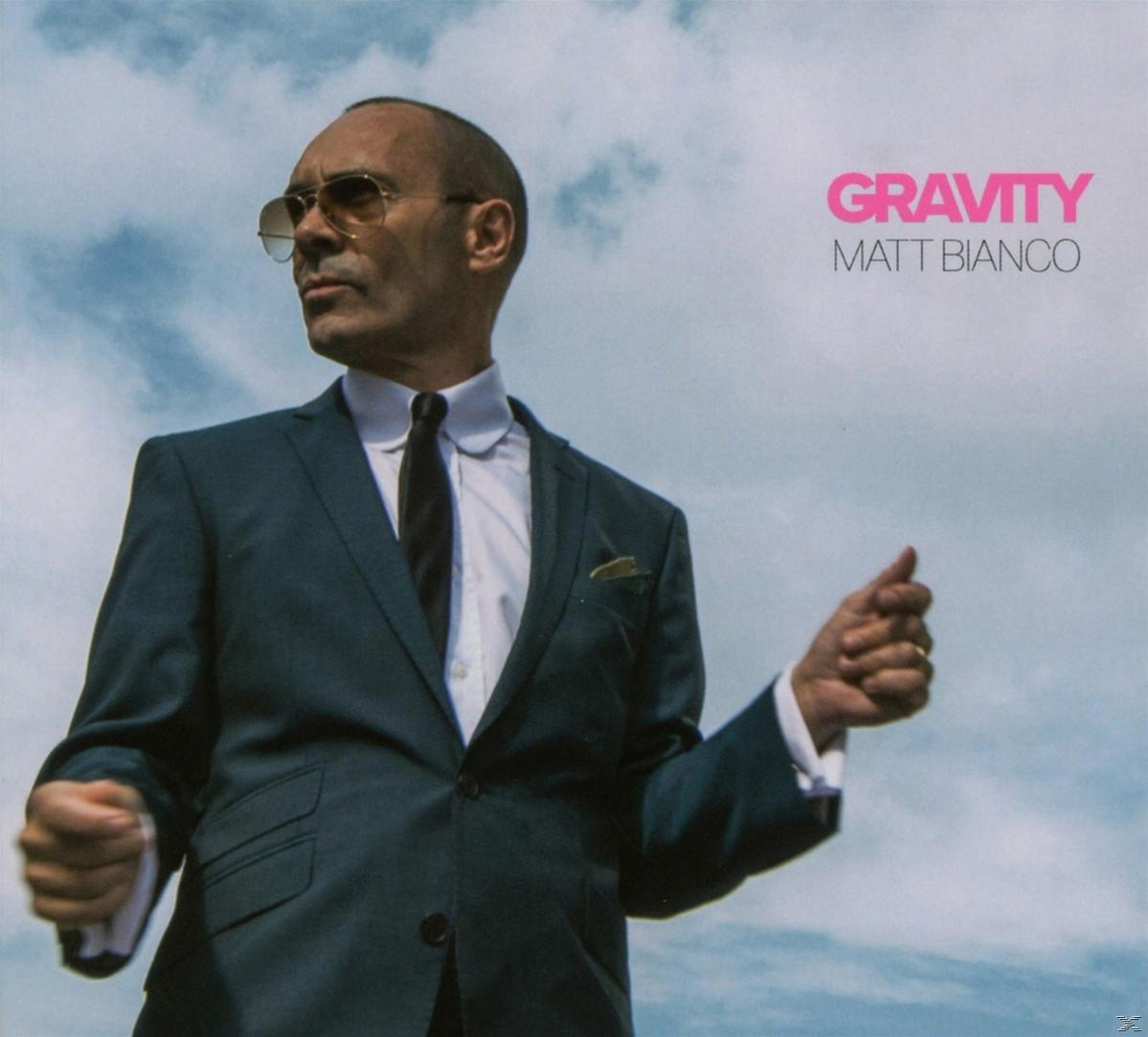 Albumcover von Matt Bianco im Anzug, Sonnenbrille und dem Text 'Gravity' in Pink.