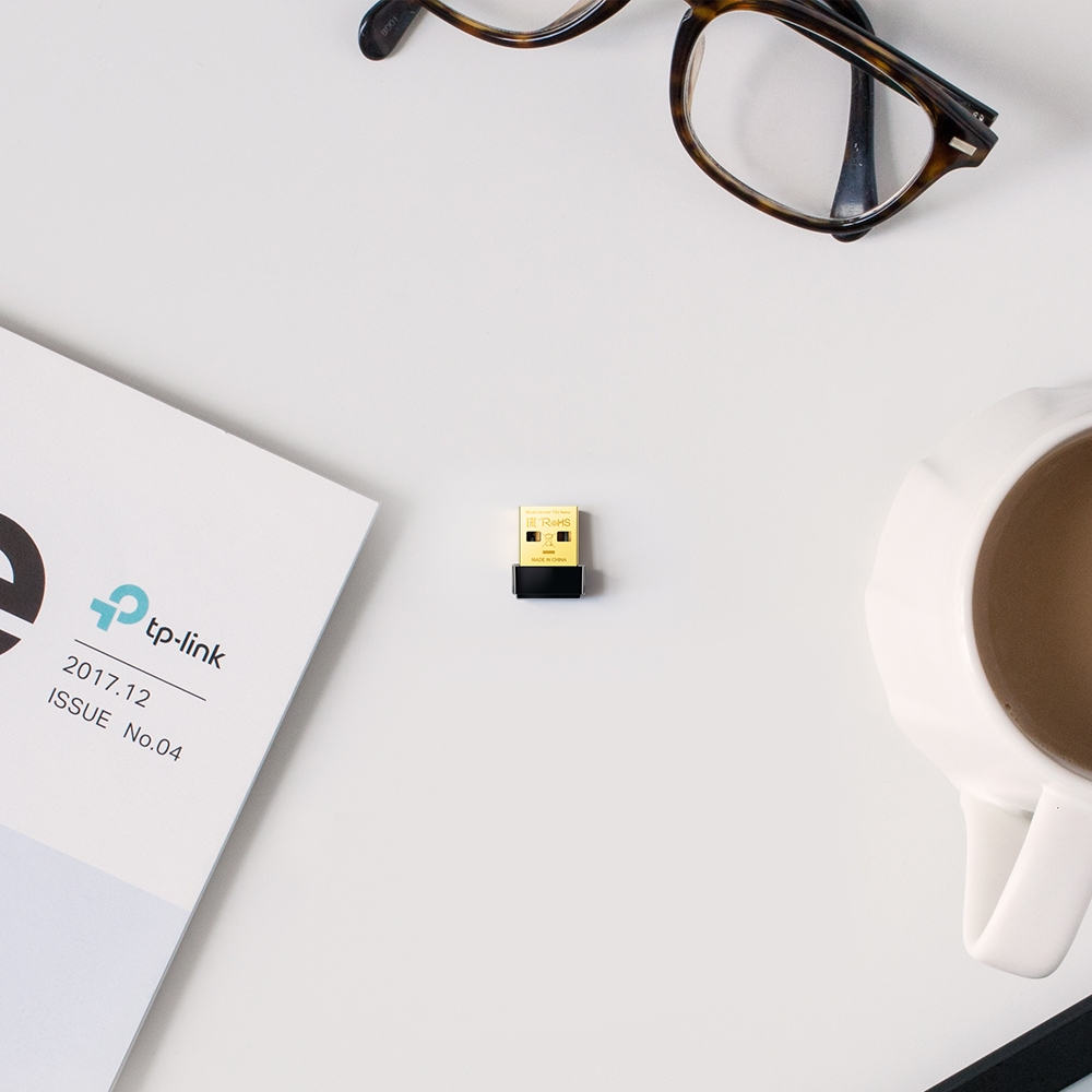 A USB drive is on a white desk. Nearby are glasses, a magazine, and a cup of coffee.