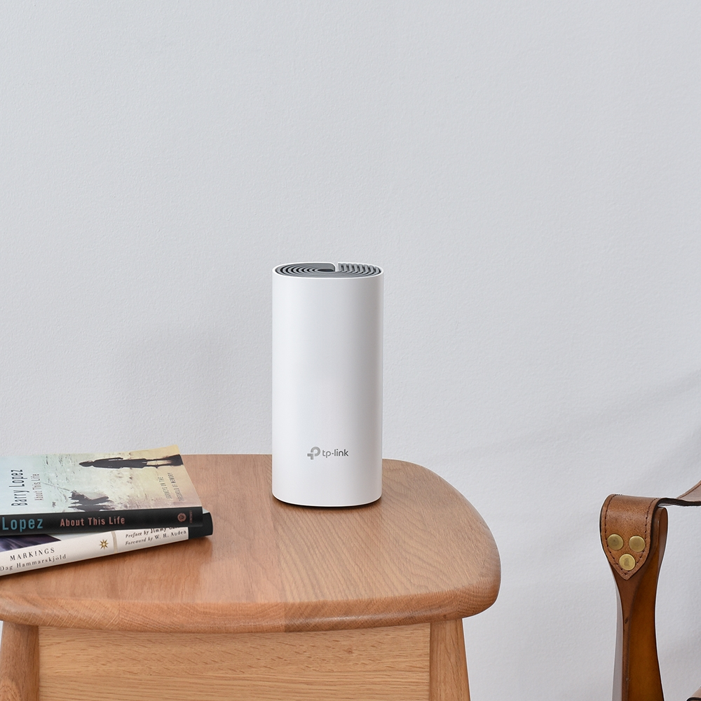 Witte cilindrische TP-Link router op een houten tafel, met boeken. Witte muur achtergrond.
