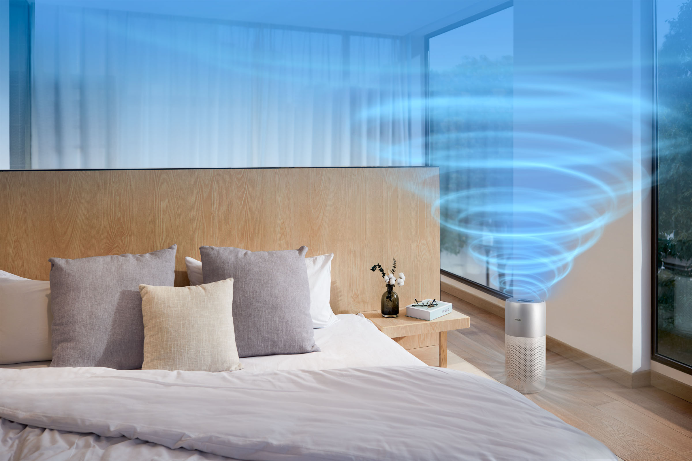Schlafzimmer mit Bett, Kissen und Luftreiniger. Blauer Luftwirbeleffekt. Großes Fenster sichtbar.