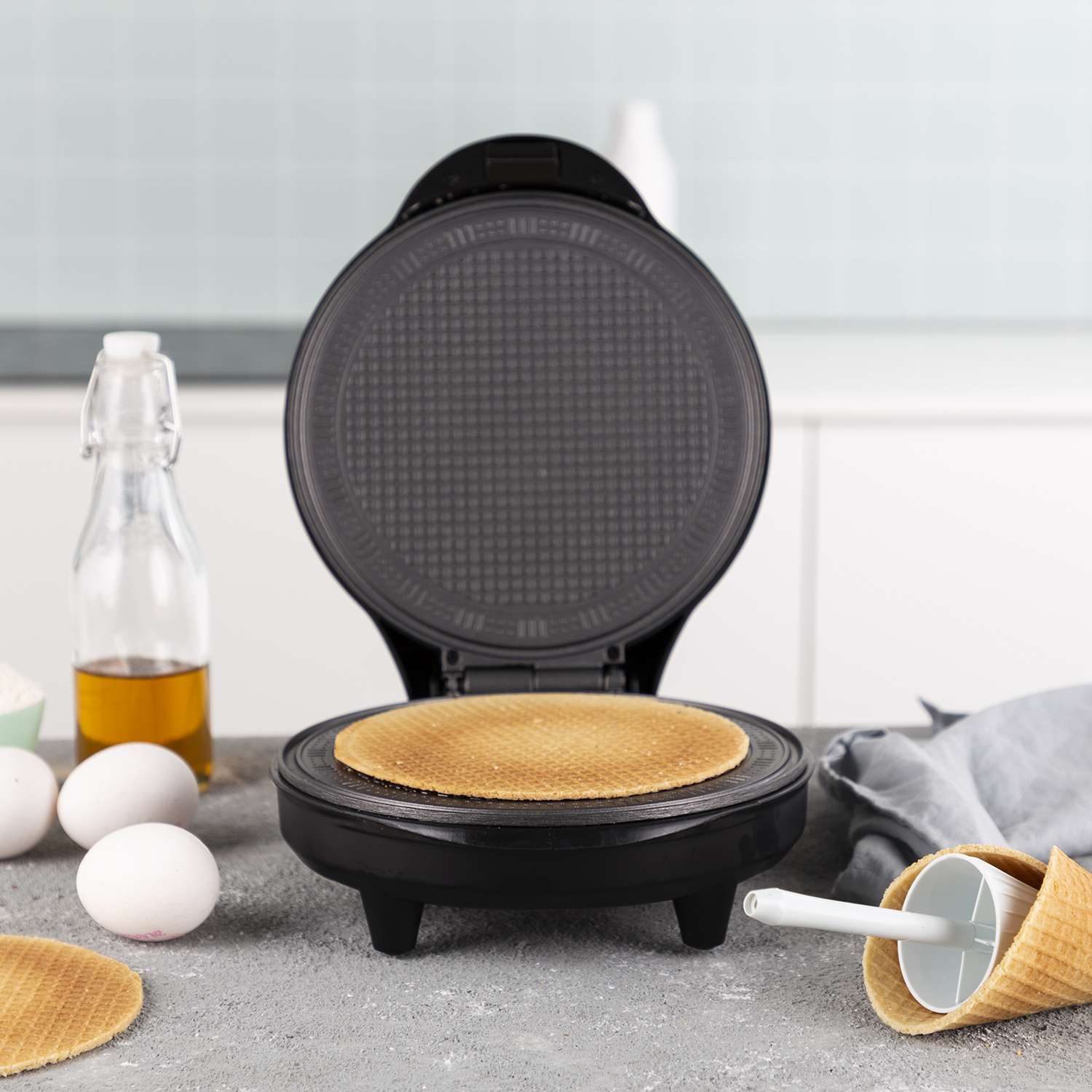 A waffle maker with a waffle on the inside, other ingredients are visible on the side.