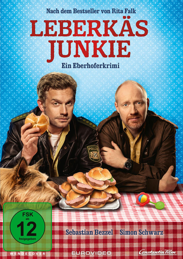 Leberkas Junkie DVD-Cover. Zwei Männer, ein Hund und Essen auf einem Tisch.