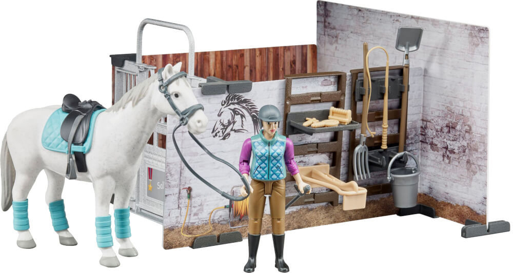 Ein weißes Spielzeugpferd mit Sattel, eine Figur einer Person in Reitkleidung und ein Stallset mit Werkzeugen.