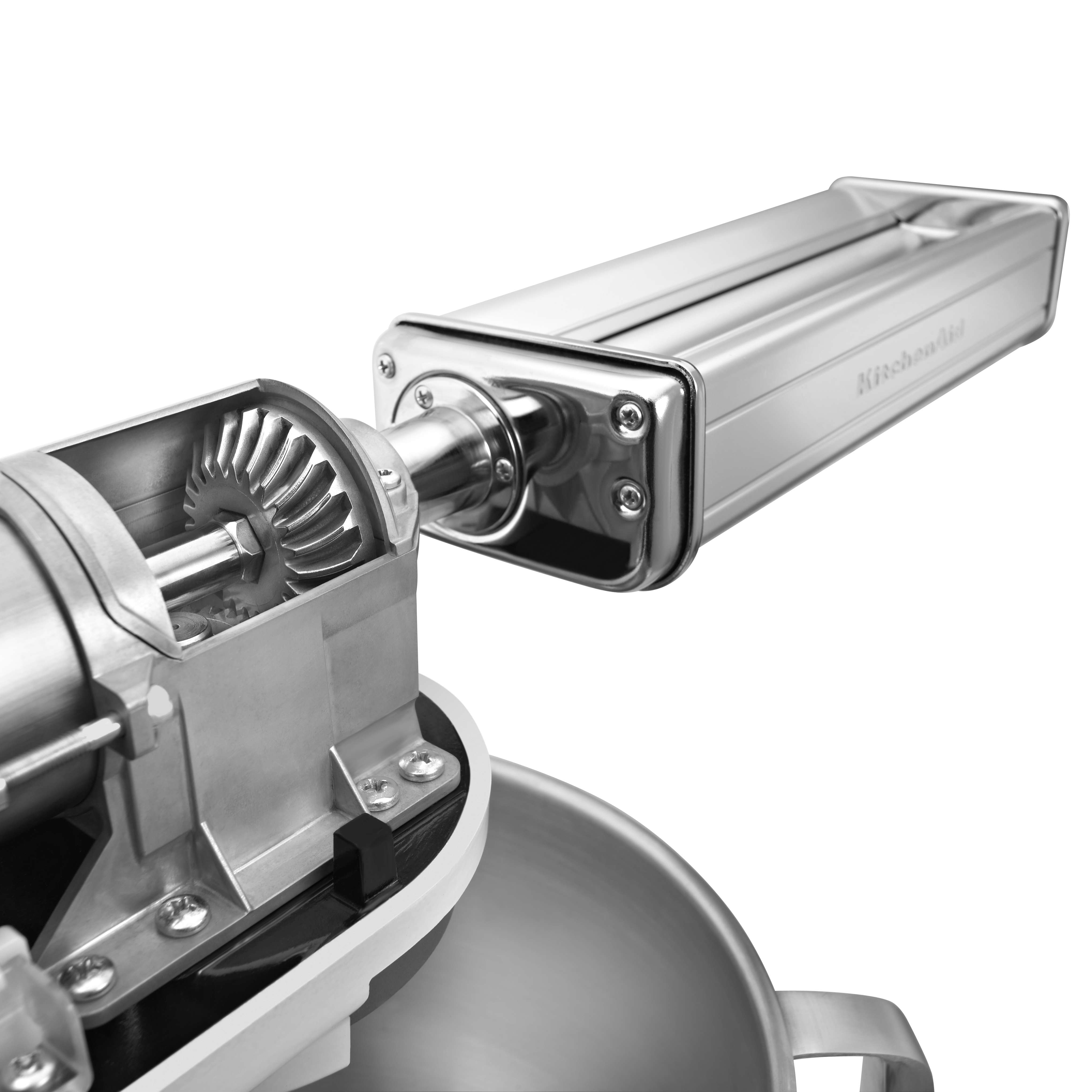 Ein KitchenAid-Nudelmaschinenaufsatz. Silberne Metallzahnradmechanismen und die Nudelrolle sind sichtbar. Der Hintergrund ist weiß.
