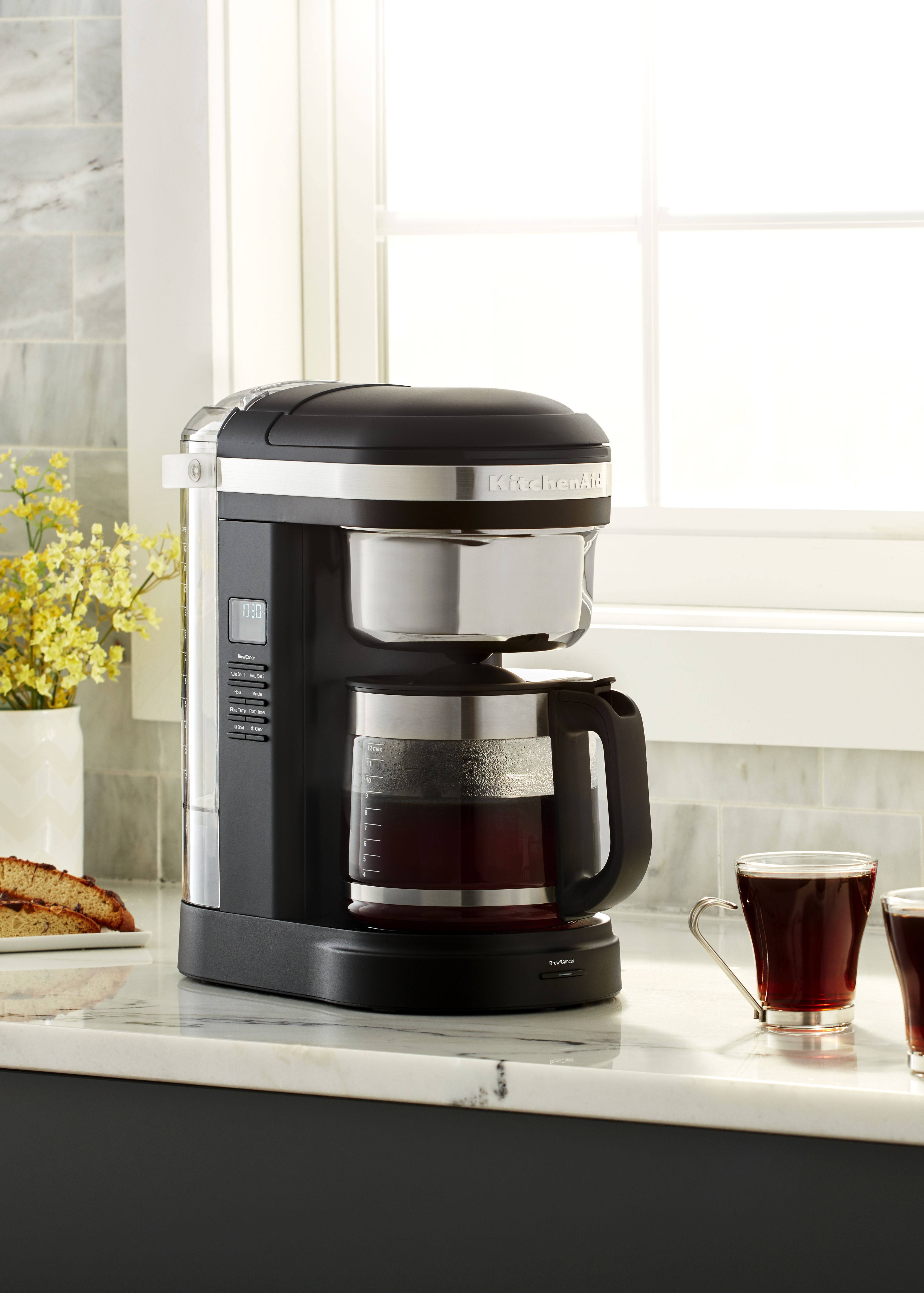 Schwarzer und silberner Kaffeebereiter mit einer Glaskaraffe gefüllt mit Kaffee, auf einer Marmortheke.