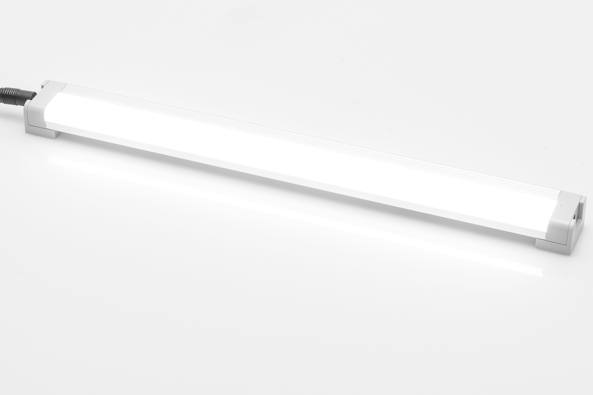 Lange, weiße LED-Lichtleiste mit grauem Rahmen auf weißer Oberfläche.