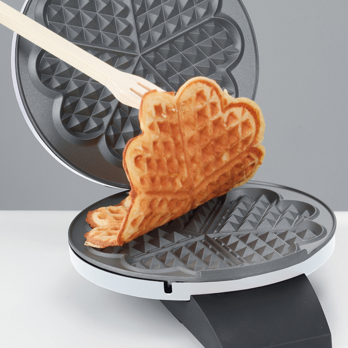 Eine Waffel wird aus einem Waffeleisen genommen.