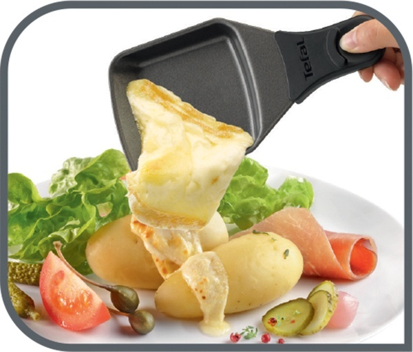 Raclette-Käse, der in Essen auf einem weißen Teller schmilzt, gehalten von einer Tefal-Pfanne.