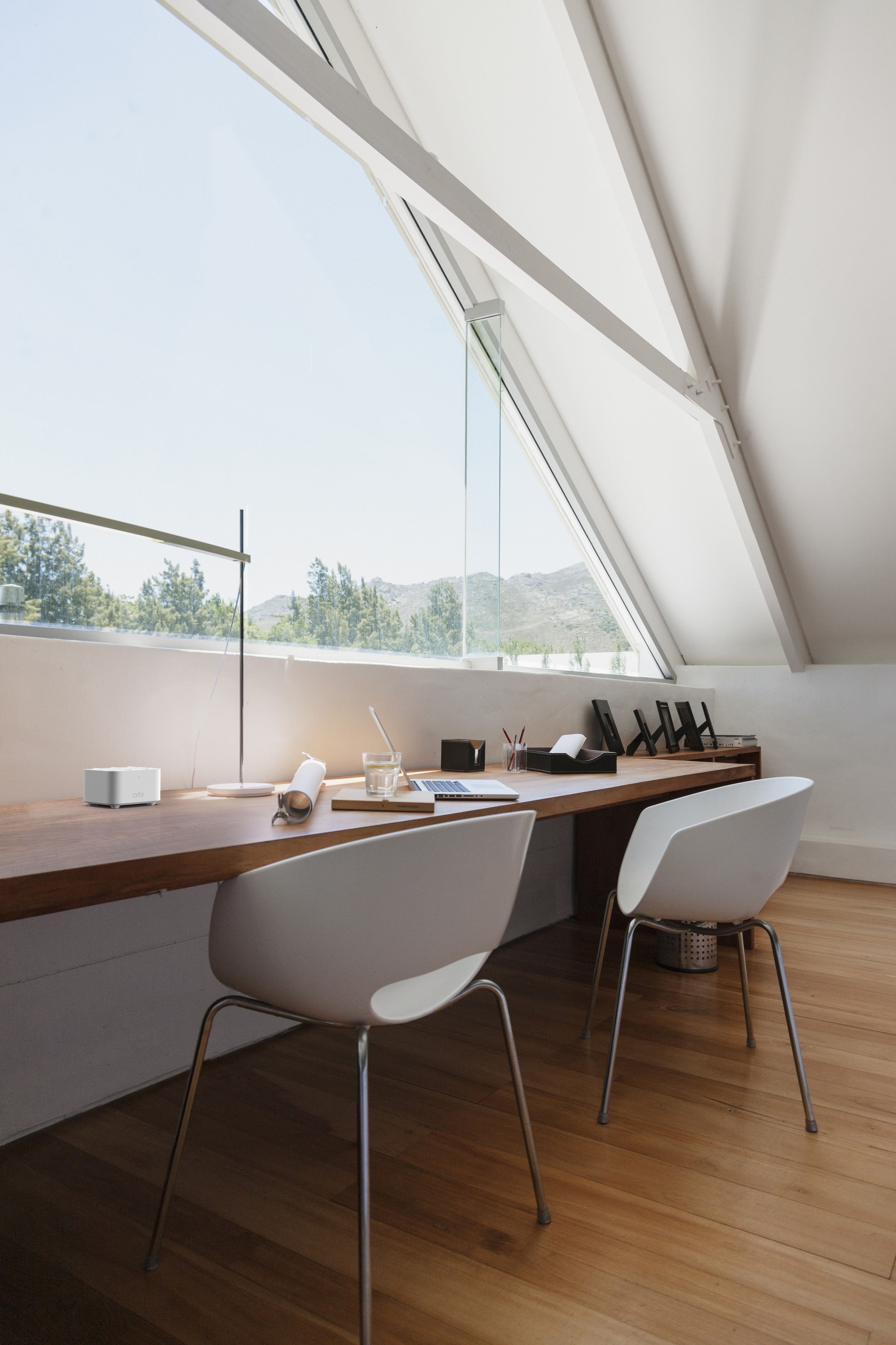 Modernes Heimbüro mit großem Fenster, Schreibtisch und zwei weißen Stühlen. Natürliches Licht.