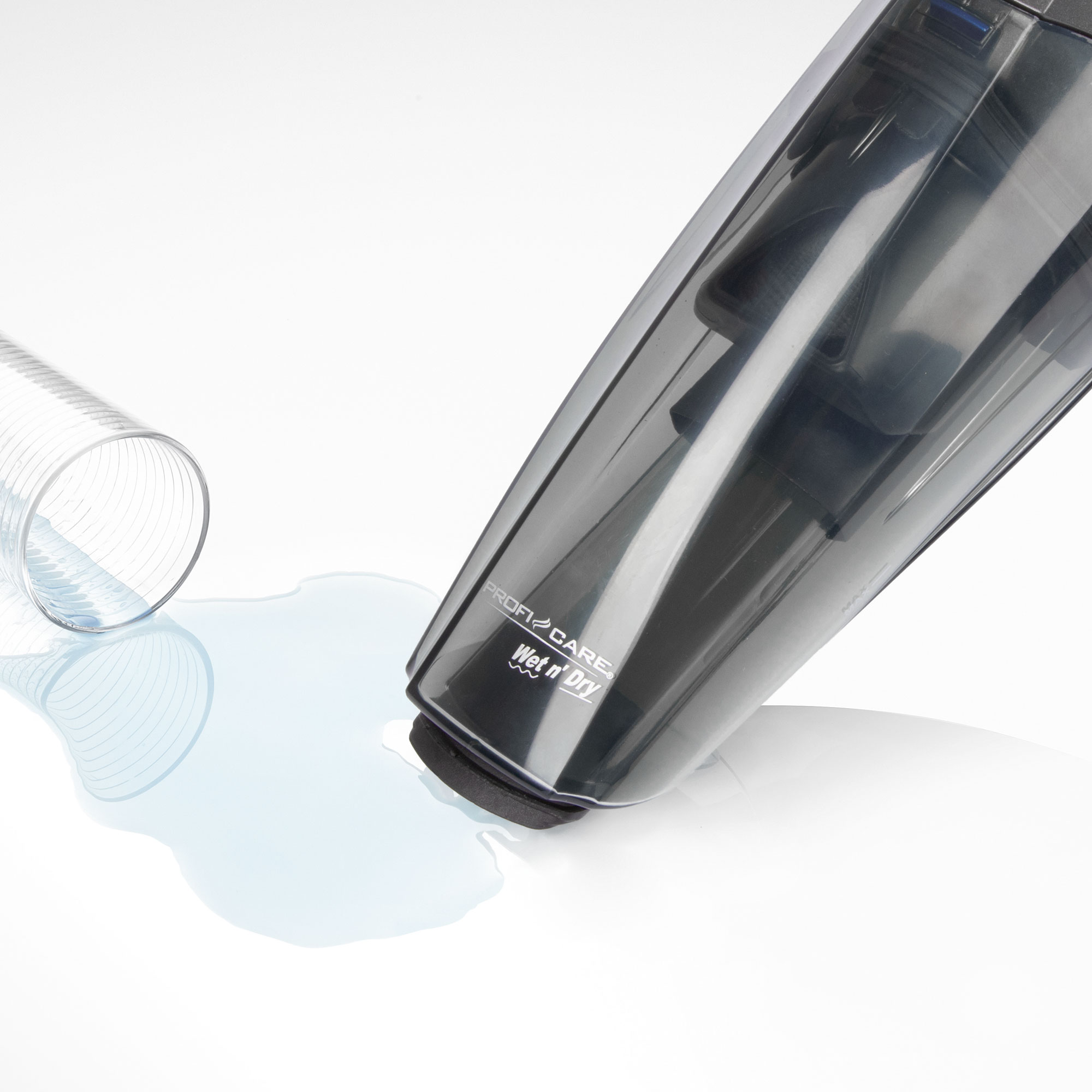 Handstaubsauger, schwarz. Wasserspritzer auf weißer Oberfläche, Saugende berührt.