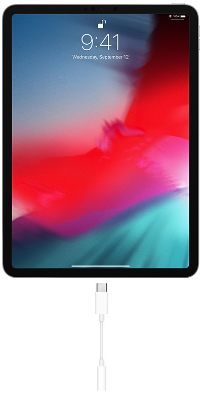 Fekete iPad fehér töltőkábellel, színes absztrakt képet mutatva.
