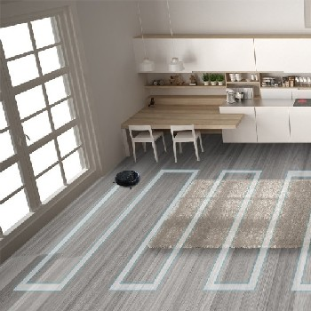 Una aspiradora robótica limpiando un piso de madera con una alfombra en una cocina moderna.