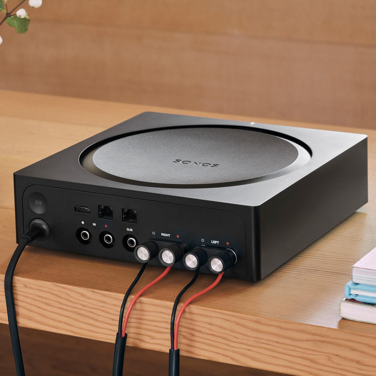 Fekete Sonos hangrendszer több bemenettel és kimenettel. Fa asztalra helyezve.
