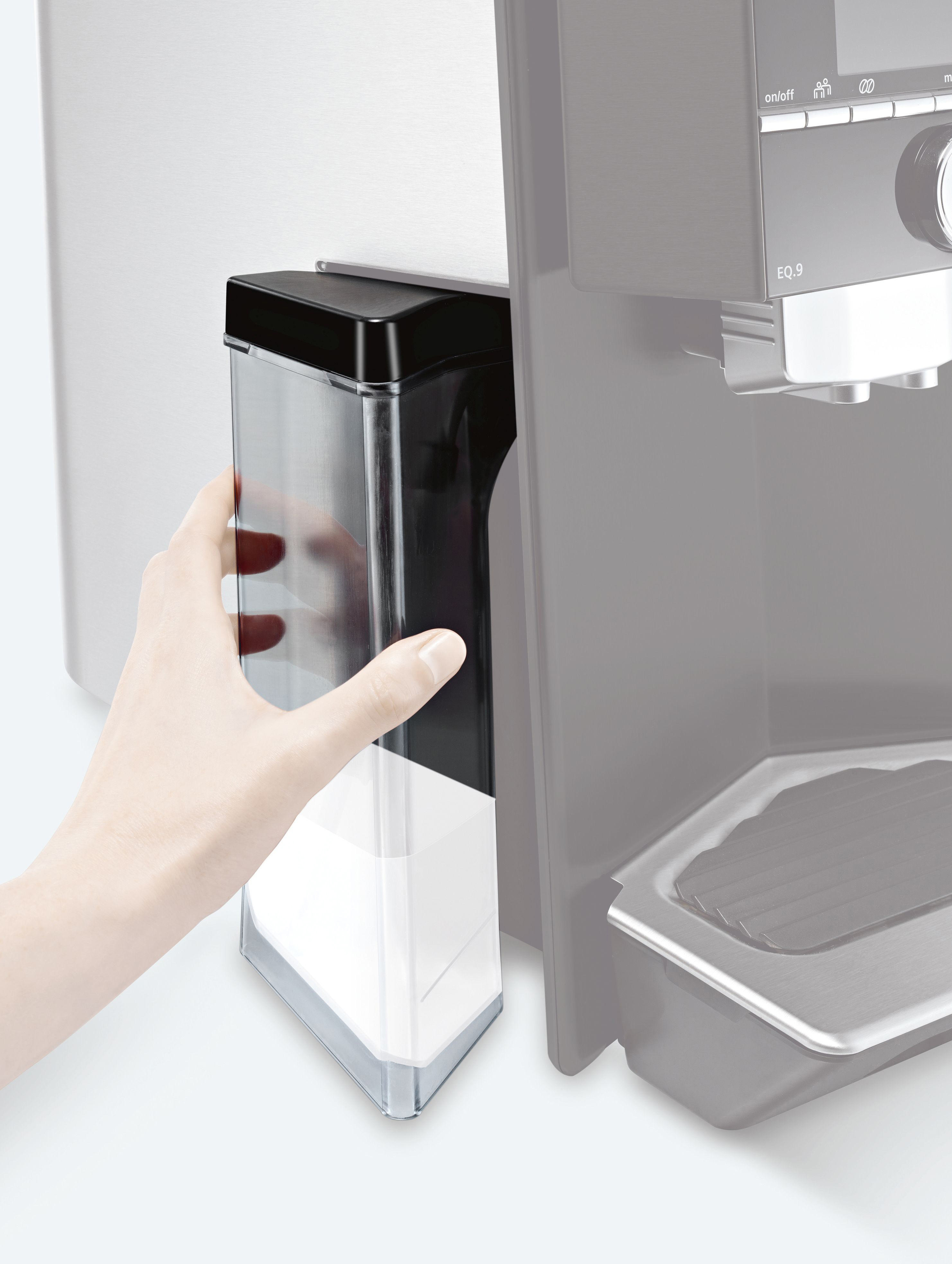 Eine Hand, die einen schwarzen Behälter in eine Kaffeemaschine einsetzt. Der Behälter ist mit weißem Pulver gefüllt.