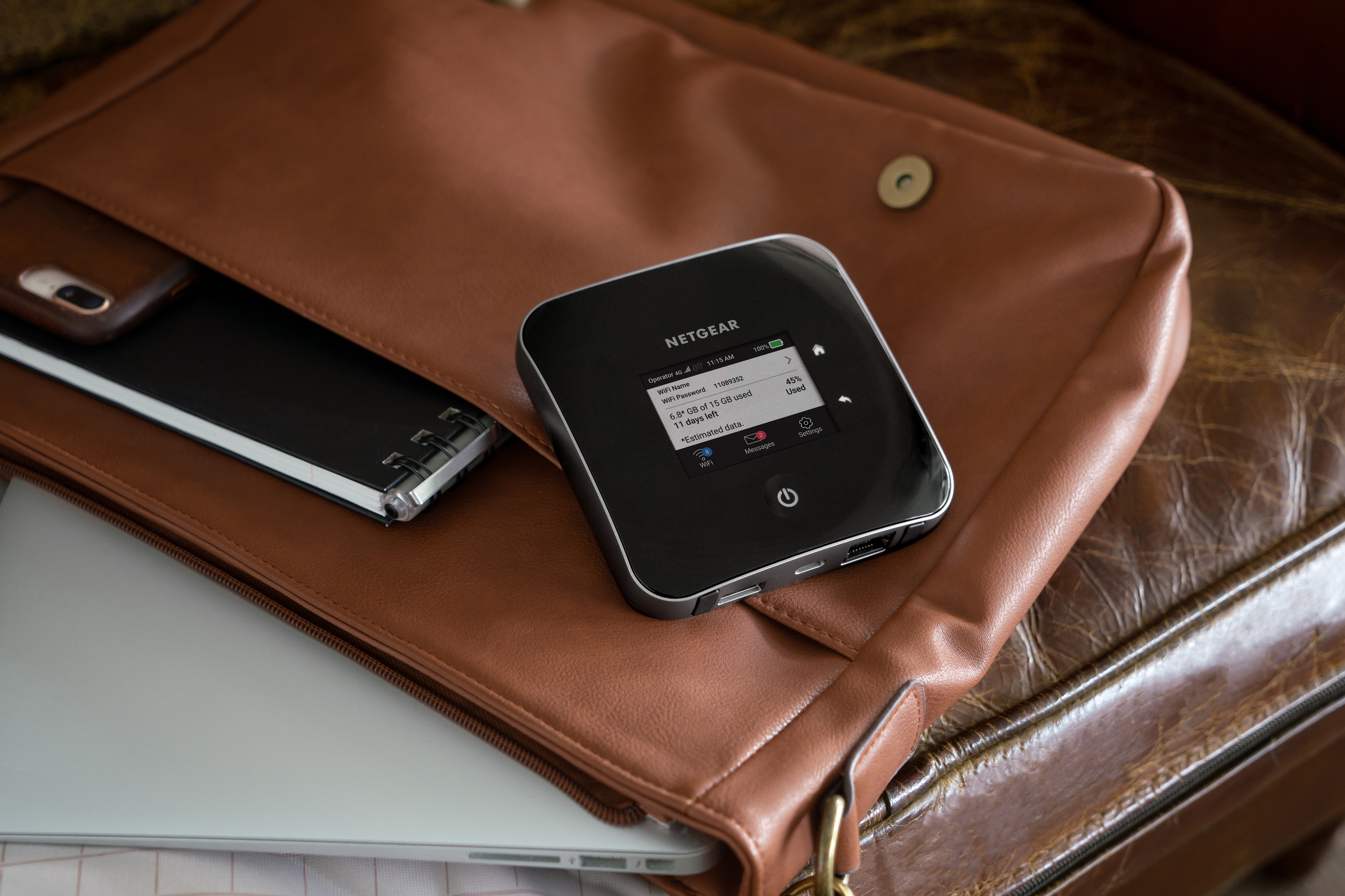 Mobile router in a brown purse. Laptop and notebook visible. Light brown leather.