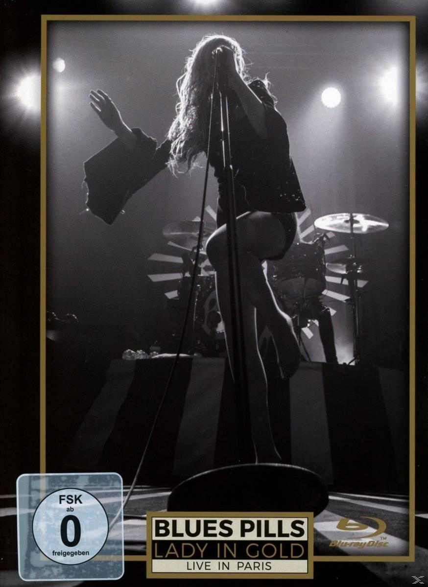Élő koncert DVD borító. Egy nő énekel mikrofonba, zenekarral és színpadi világítással.
