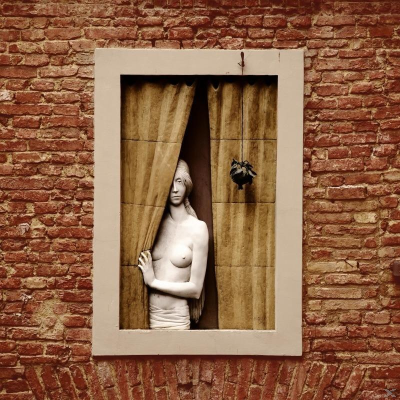 Eine Steinskulptur einer Frau in einem Fenster, mit einem hängenden Ornament und einer Backsteinmauer.