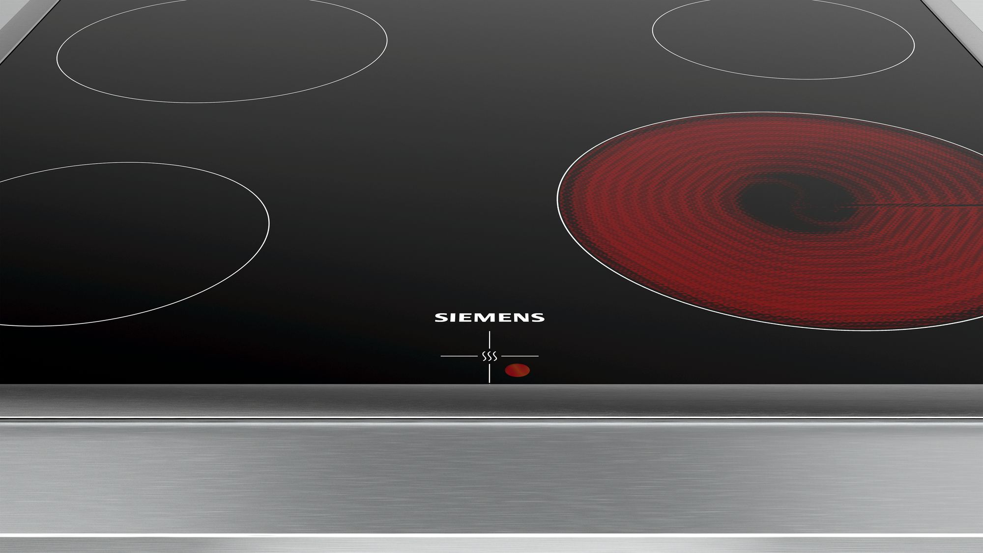 Gros plan d'une plaque de cuisson électrique noire avec quatre feux, un rouge vif.