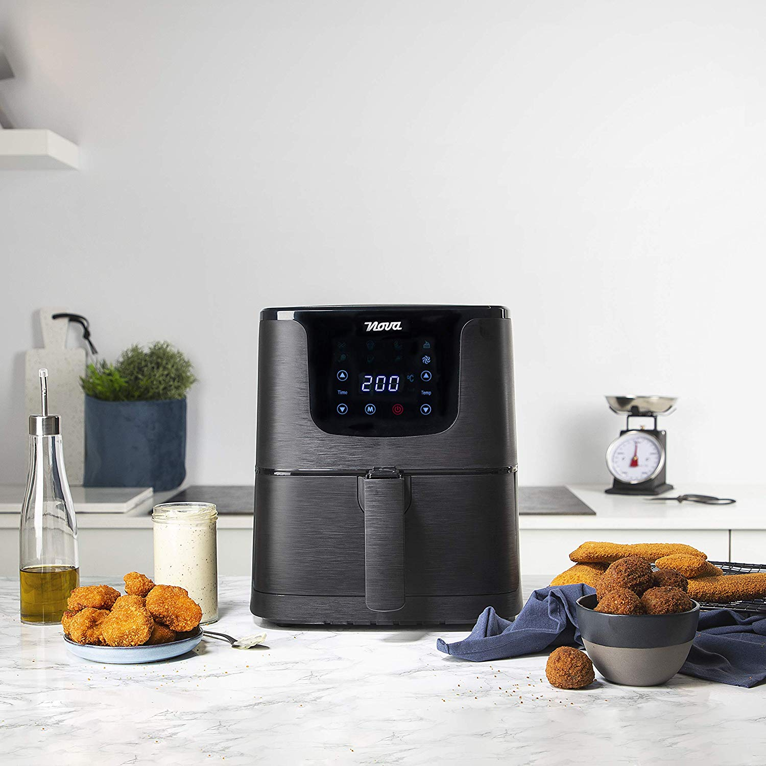 Black air fryer on a counter, with food, and a scale.