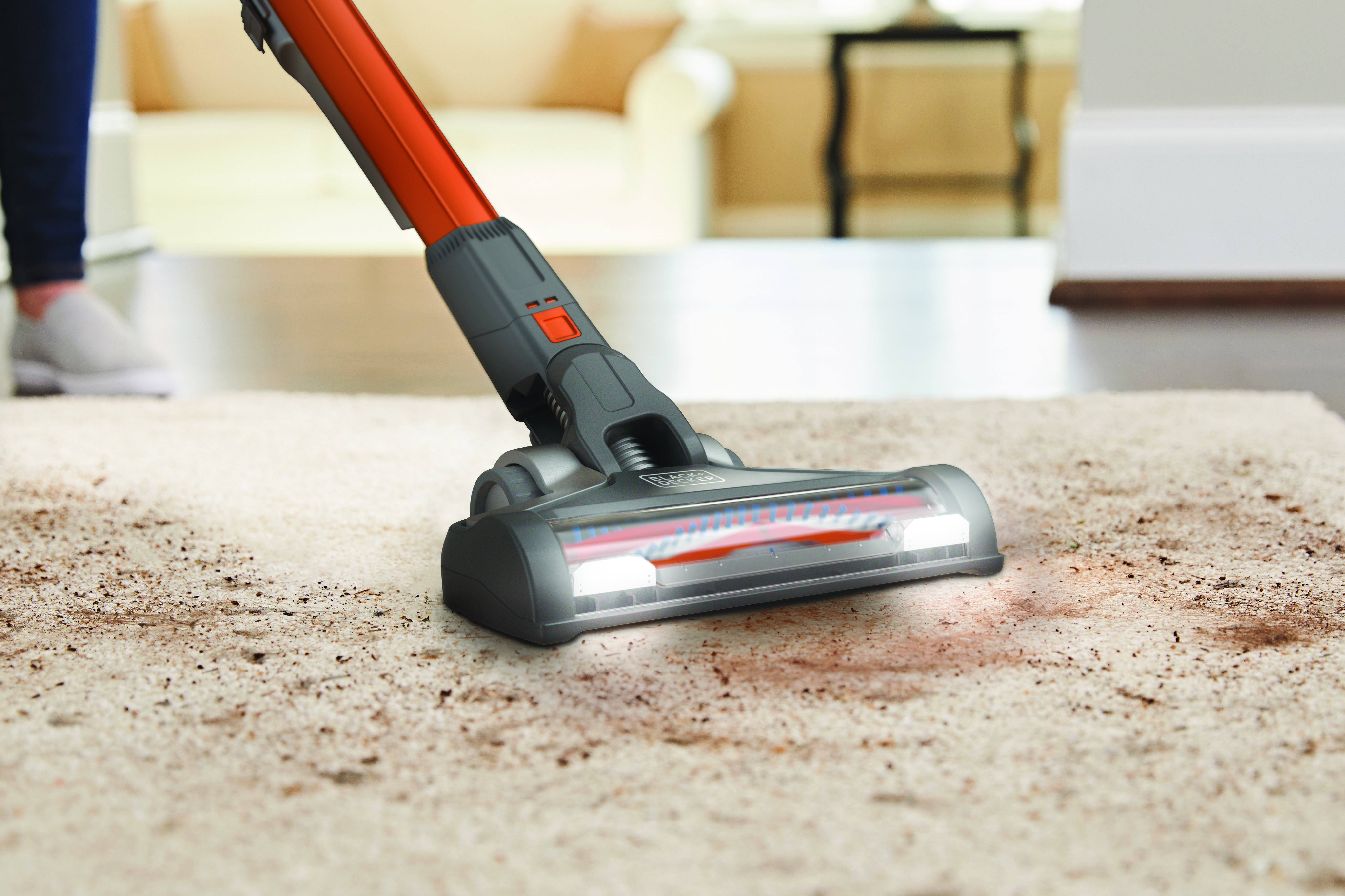 Vacuum cleaner head cleaning a rug. The vacuum is orange and gray.