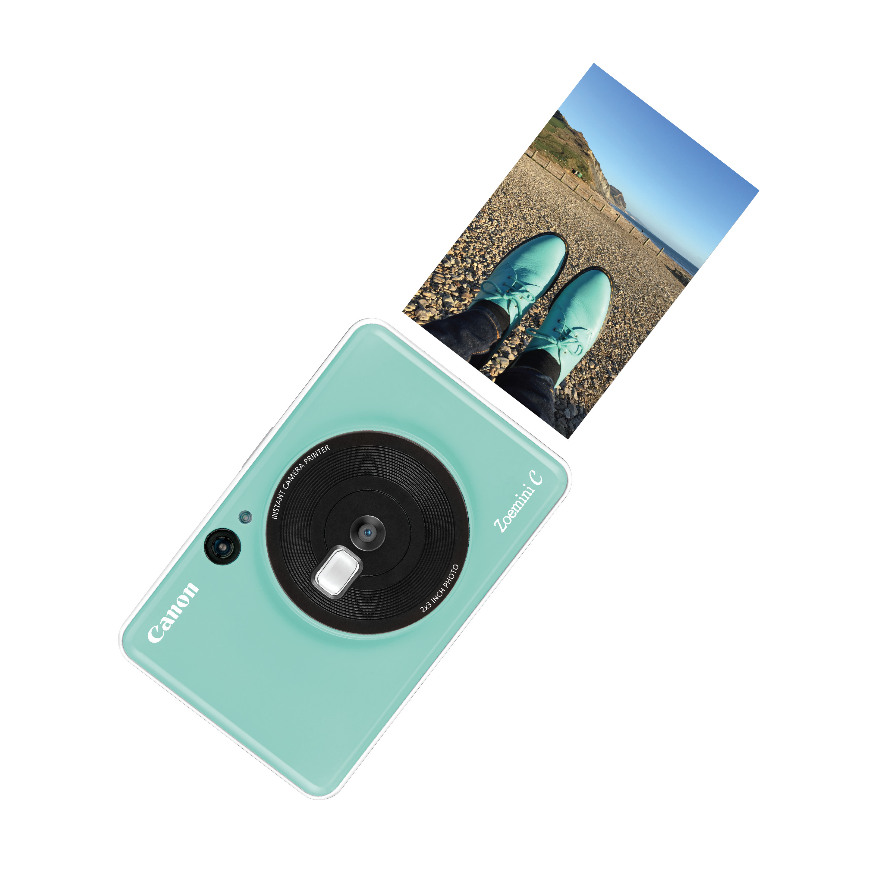 A mint green Canon Zoemini C instant camera with a photo being printed.