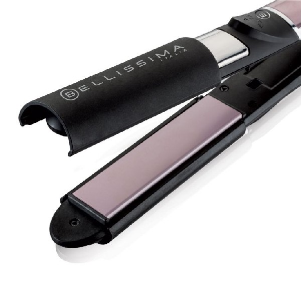 Primer plano de una plancha de pelo negra y rosa, abierta, sobre una superficie blanca.