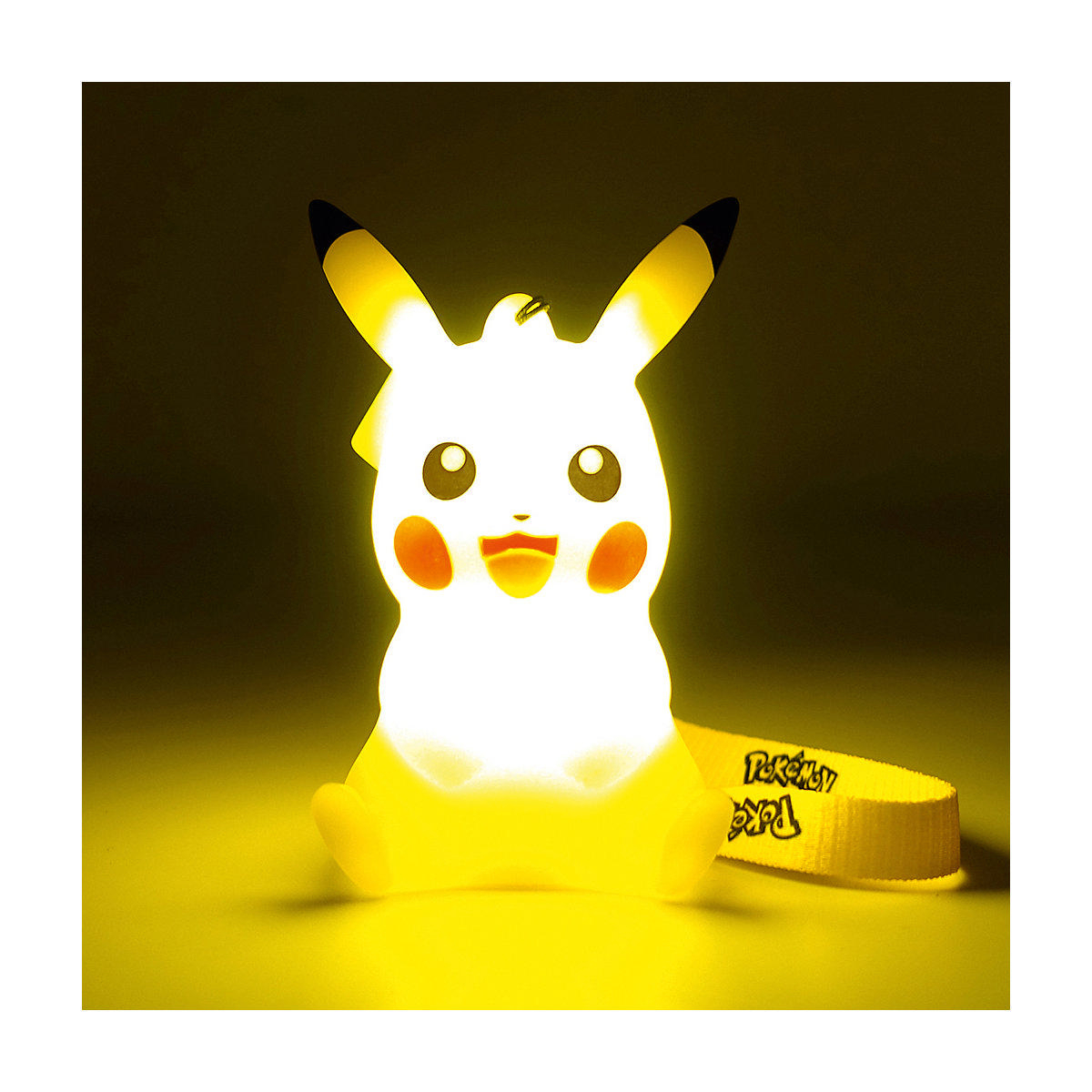 Pikachu-Lampe auf gelbem Untergrund. Sie leuchtet und hat einen Riemen mit dem Pokémon-Logo.