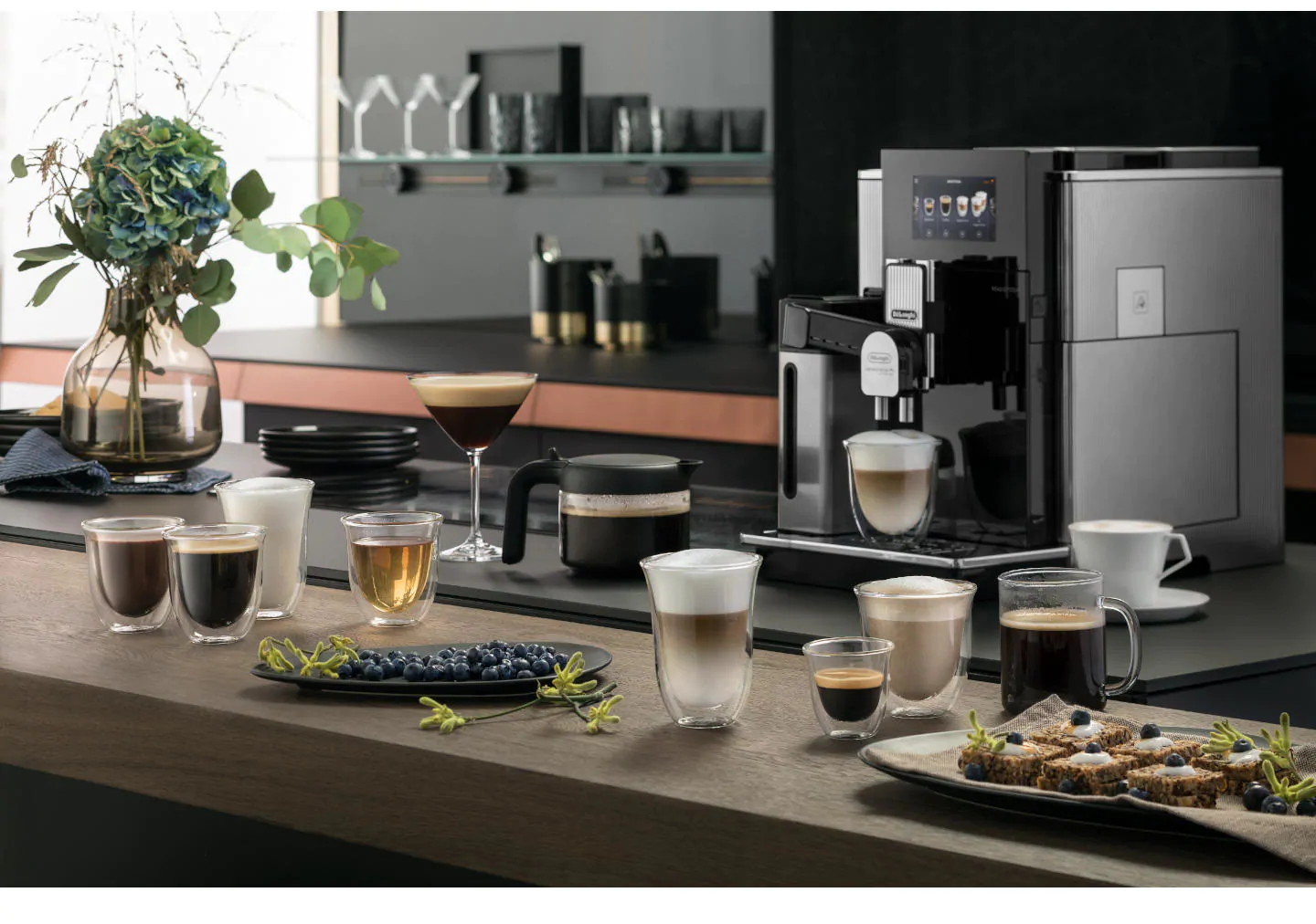 Machine à café avec diverses boissons au café et pâtisseries sur un comptoir.