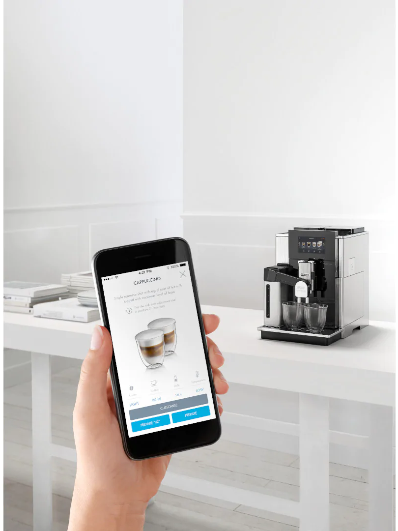 Une personne utilise un smartphone pour contrôler une machine à café. La machine est à droite.